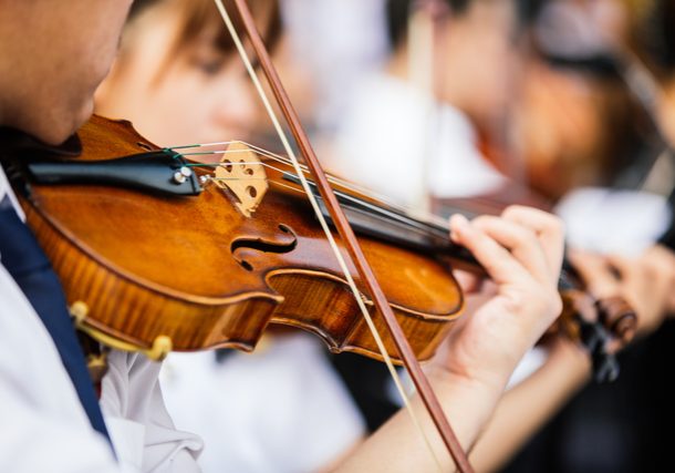 Close up violin player hands, student violinist playing violin in orchestra concert